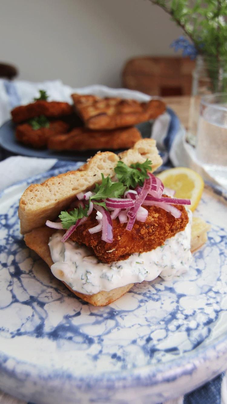 Focaccia sandwich med panert fisk, syltet rødløk og persilledressing